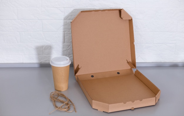 taza de café desechable y caja de pizza abierta