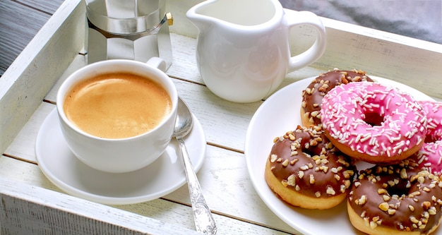 Taza de café con donas en una bandeja de madera