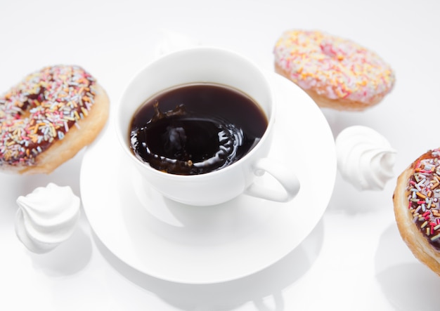 Taza de café con donas y merengues en movimiento