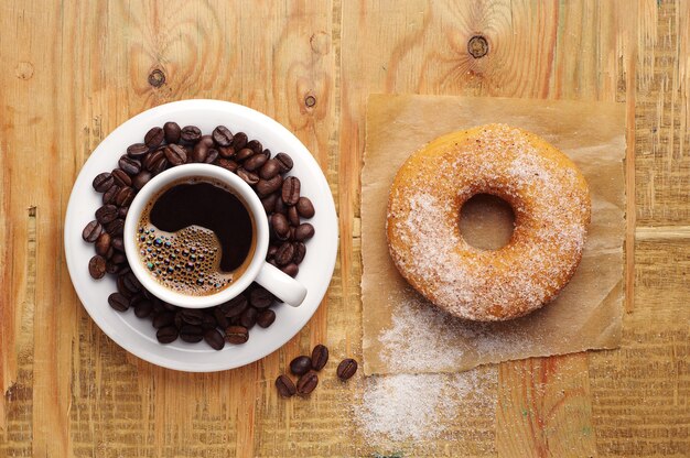 Taza de café y donut sobre fondo de madera