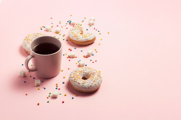 Taza de café, Donuts dulces sabrosos frescos sobre un fondo rosa. El concepto de comida rápida, panadería, desayuno, dulces. Minimalismo Lay Flat, vista superior, espacio de copia.