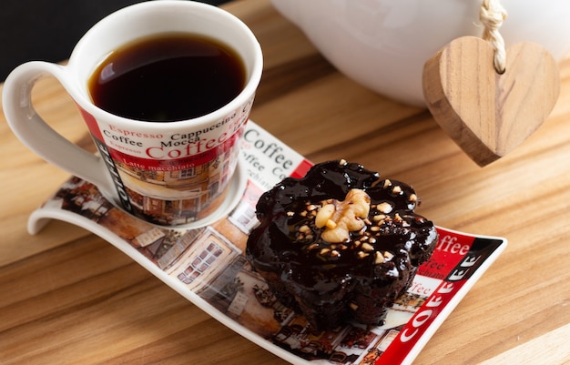 Taza de café y un dulce de chocolate debajo de la mesa de madera.