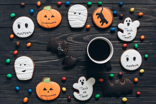 Una taza de café con dulces de colores y panes de jengibre miedo en el Halloween.