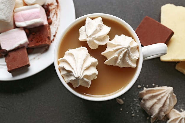 Taza de café y dulces sobre fondo de madera negra