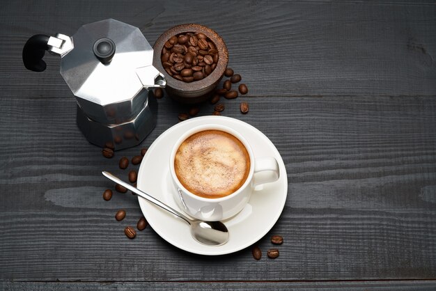 Taza de café espresso y cafetera moka en la mesa de madera oscura.