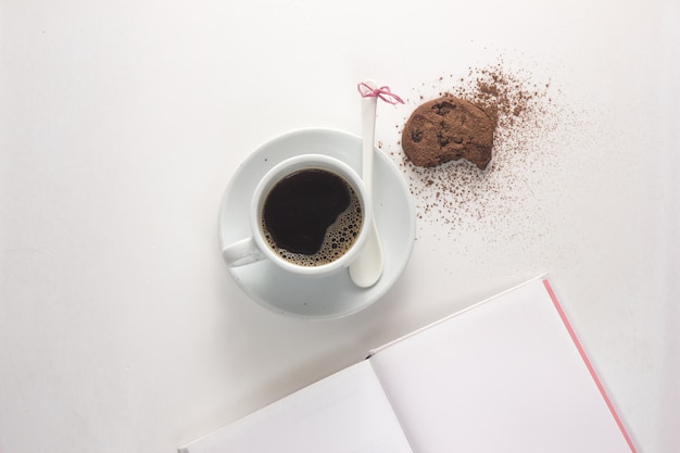 Taza de café espresso con libro sobre la mesa.