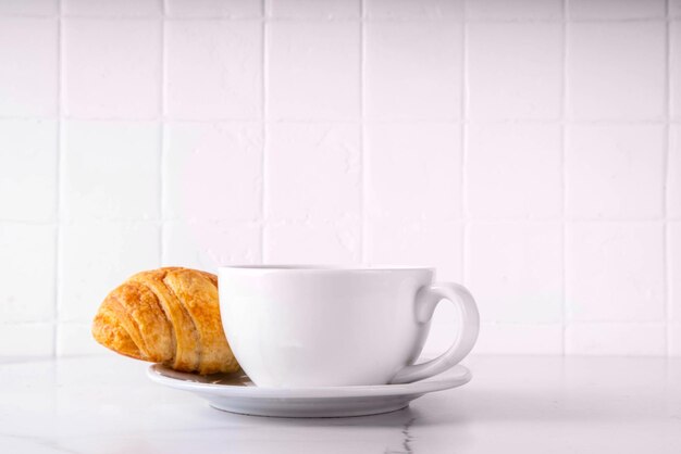 Una taza de café espresso negro con un croissant.