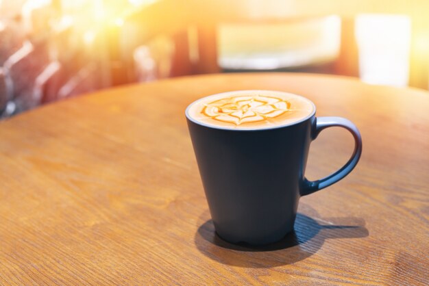 Taza de café con espuma en forma de flor en la mesa de madera