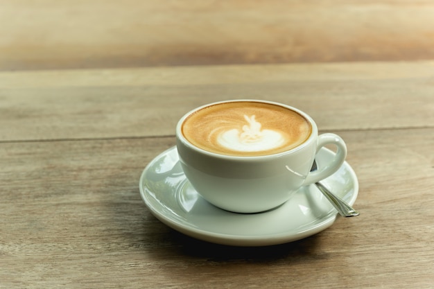 Taza de café con espuma en la tabla de madera.