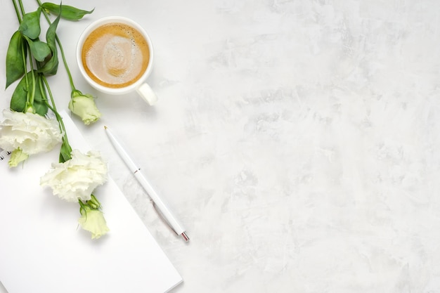 Taza de café, eustoma, cuaderno y bolígrafo sobre fondo de hormigón. Vista superior plana sobre la cabeza. Copiar el fondo del espacio