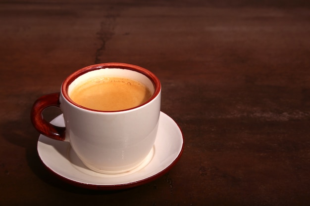 Foto una taza de café exprés sobre una superficie de madera oscura