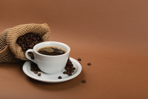 Taza de café expreso y granos de café en bolsa de arpillera