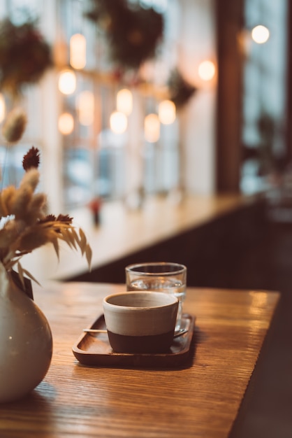 Taza de café expreso y vaso de agua en la mesa de madera