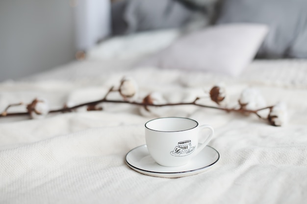 Taza de café y flor de algodón. Desayuno en la cama.