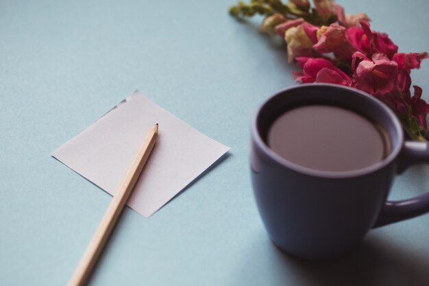 Taza de café con flor de primavera y notas de buenos días en el cuadro azul