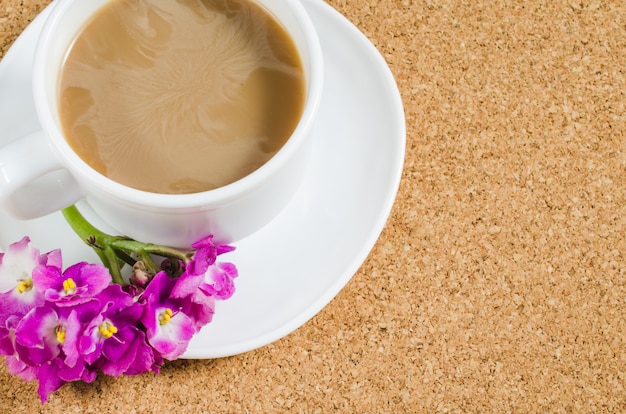 Taza de café con las flores en tarjeta del corcho.