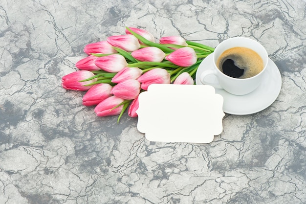 Taza de café con flores de tulipán y etiqueta de papel blanco