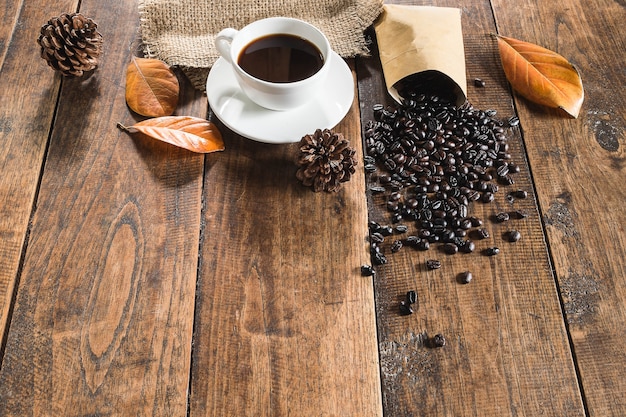 Taza de café de fondo y granos de café en el piso de madera