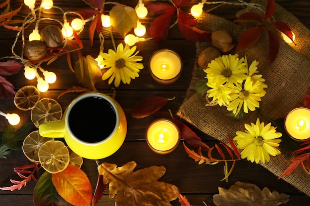 taza de café en el fondo de otoño con hojas y flores