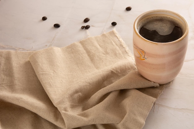 Taza de café en un fondo de piedra de mármol con servilleta beige en la vista delantera