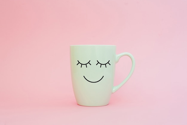 Taza de café en fondo rosado con la cara feliz de la sonrisa