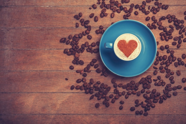 Taza de café con forma de corazón sobre una mesa de madera