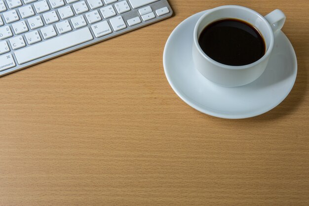 Taza de café fragante en un papel y teclado de la mañana