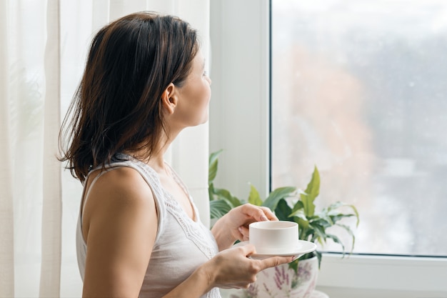 Taza de café fresco de la mañana en manos de mujer