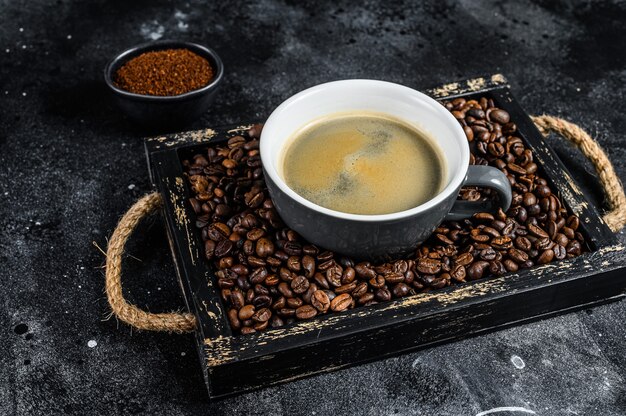 Taza de café y frijoles en bandeja de madera vieja.