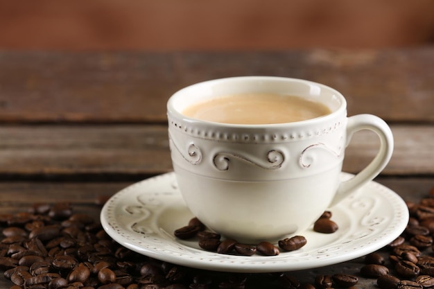 Taza de café y frijoles en la mesa de madera de cerca