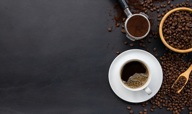 Taza de café y frijoles en la mesa de madera negra