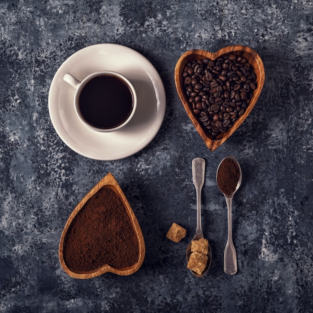 Taza de café, frijoles y polvo molido sobre la superficie de piedra