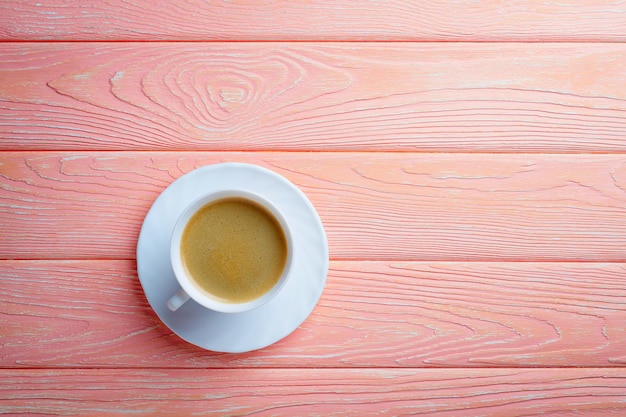 Taza de café y frijoles sobre un fondo de madera rosa