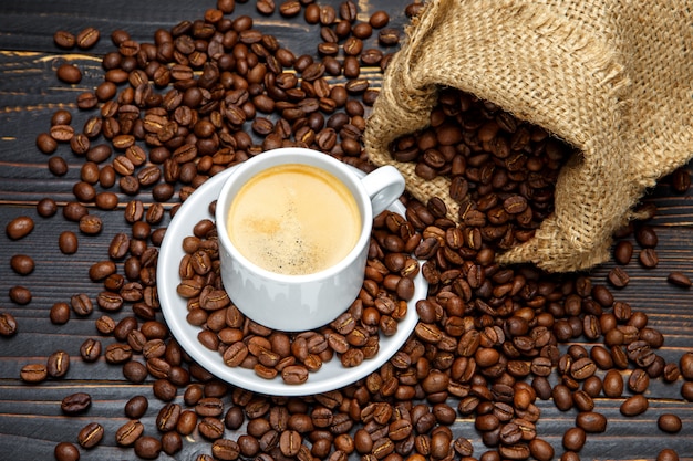 Taza de café y frijoles sobre fondo de madera