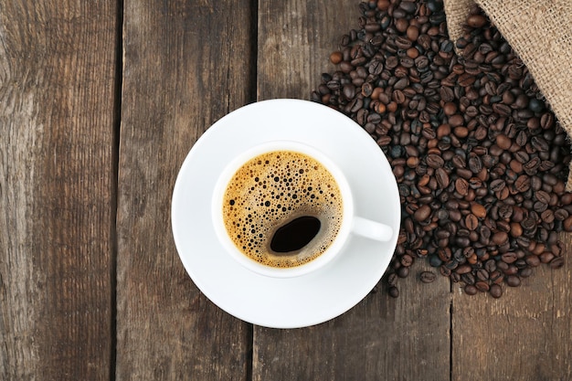 Taza de café con frijoles sobre fondo de madera