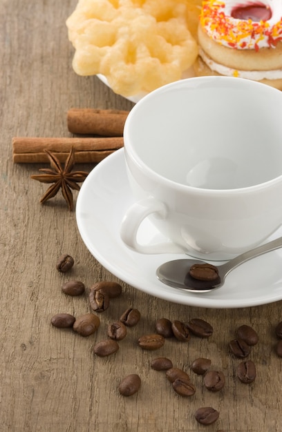 Taza de café con frijoles y tortas sobre tablero de madera