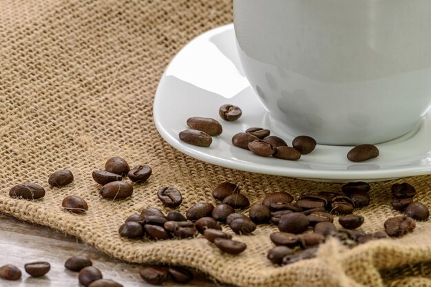 Taza de café con frijoles tostados en un saco de arpillera