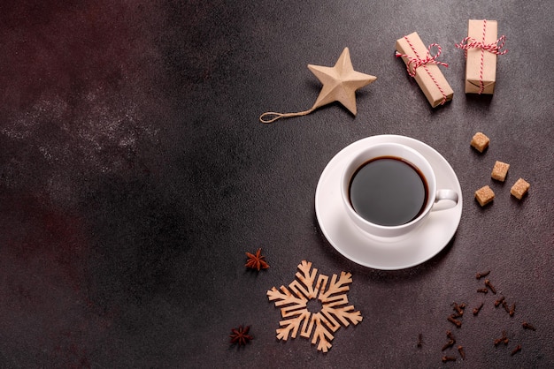 Una taza de café fuerte en la mesa de Navidad con ramitas de abeto y juguetes. Preparándose para las vacaciones