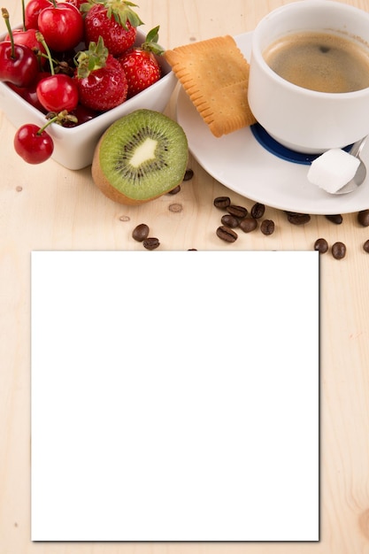 Taza de café con una galleta y azúcar sobre una mesa de madera con bayas rojas con una hoja de papel en blanco para texto Comida simulada receta de invitación de papel de tarjeta blanca vacía