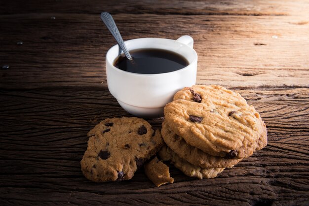 Taza de café con galleta de chocolate sobre fondo de madera oscuro