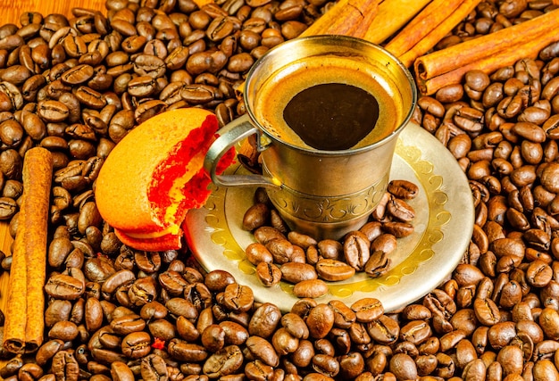 Una taza de café con una galleta a medio comer entre granos de café.