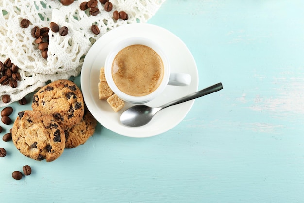 Taza de café y galleta sabrosa sobre fondo de madera de color