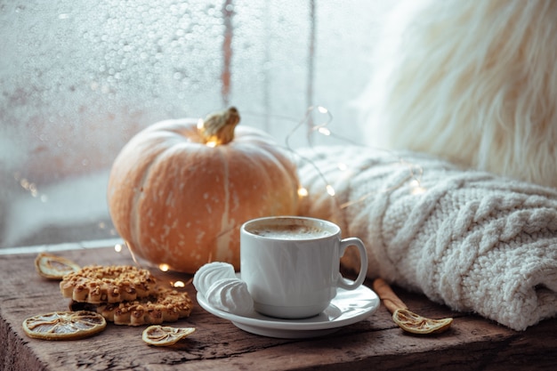 Una taza de café, galletas y calabaza en el alféizar de la ventana. Concepto de otoño.