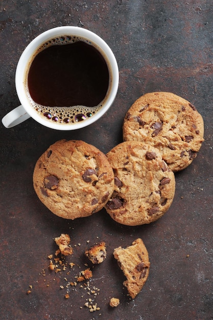 Taza de café y galletas de chispas de chocolate en el fondo de metal oxidado vista superior