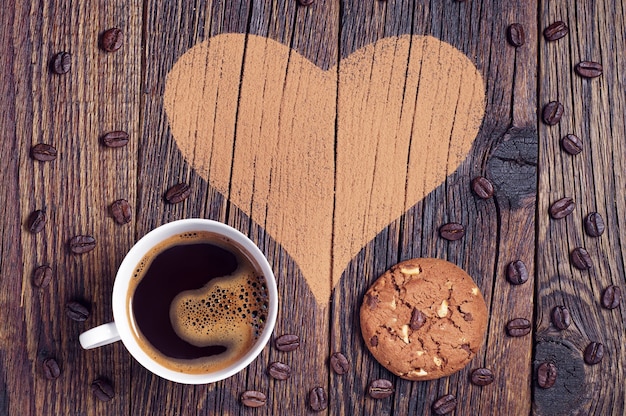 Taza de café, galletas de chispas de chocolate sobre fondo con corazón