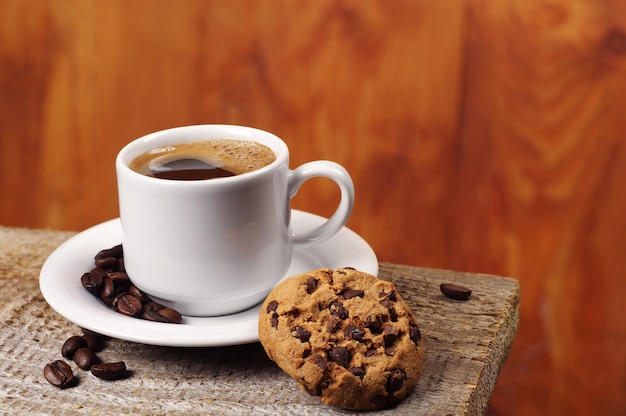 Taza de café con galletas de chocolate en la mesa de madera antigua