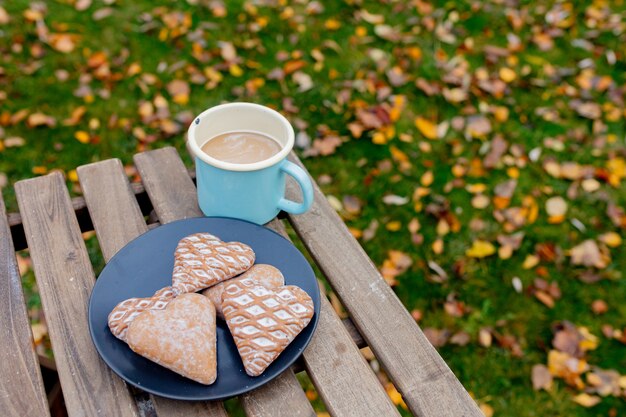 Taza de café con galletas en forma de corazón sobre una mesa en la temporada de otoño