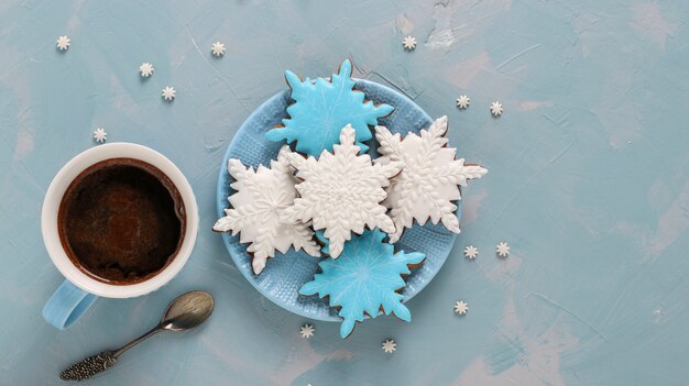 Taza de café y galletas de jengibre en forma de copos de nieve en azul claro