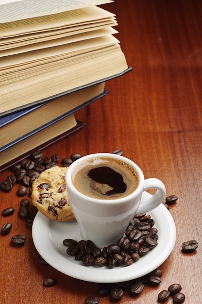 Taza de café, galletas y libros sobre la mesa