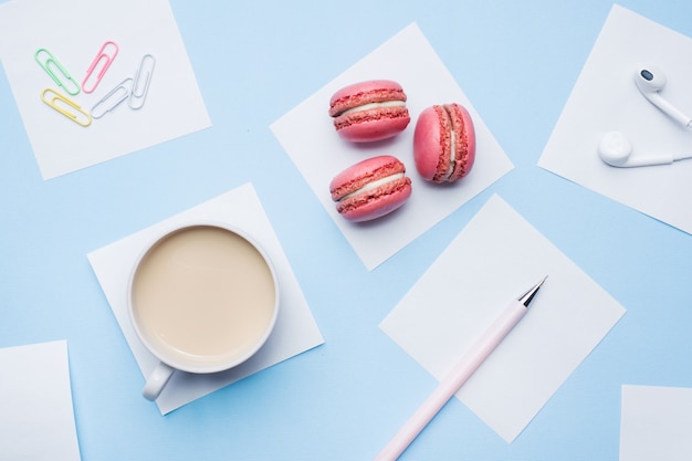 Foto taza de café, galletas de macarrón y bloc de notas con plano